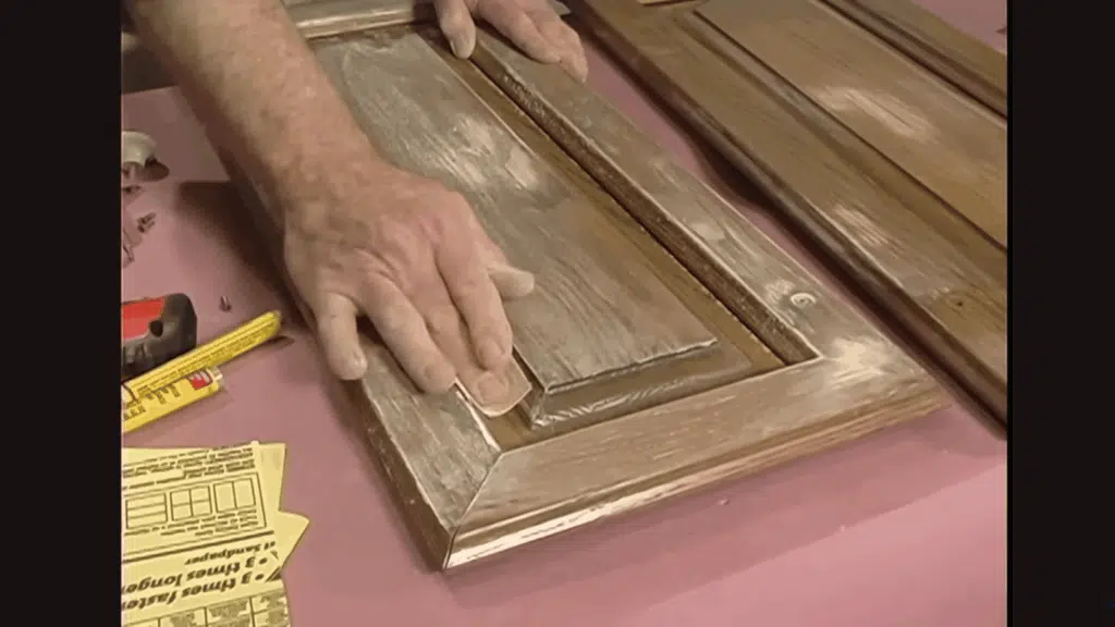 sanding cabinet door with sandpaper to prep for refinishing.