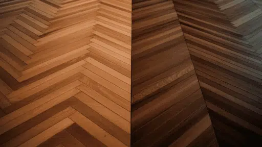 side by side floor comparison showing herringbone pattern on the left and chevron pattern on the right in warm wood tones