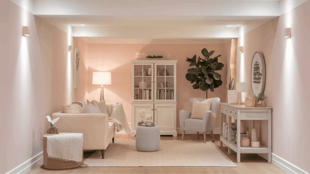 soft blush pink basement walls with white trim, light decor, cozy seating, and bright, airy finish in a small space