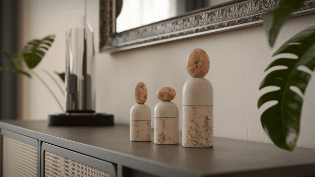 three small sculptural figurines in matte white and stone tones grouped in varying heights on a styled console table