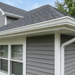 view of house roof edge showing fascia soffit and gutter with gray siding and shingles on suburban home