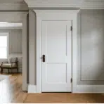 white painted interior doors and trim in a modern hallway with gray walls, crown molding, and wood flooring