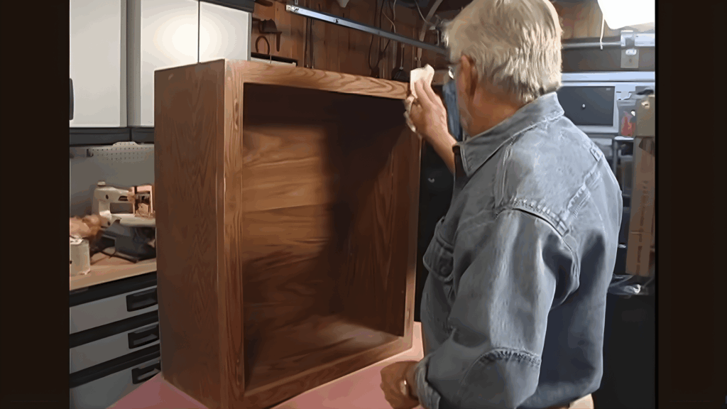 wiping cabinet box interior with cloth to remove dust and residue.