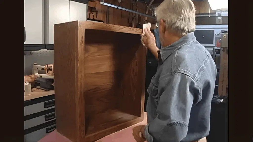 wiping cabinet box interior with cloth to remove dust and residue.
