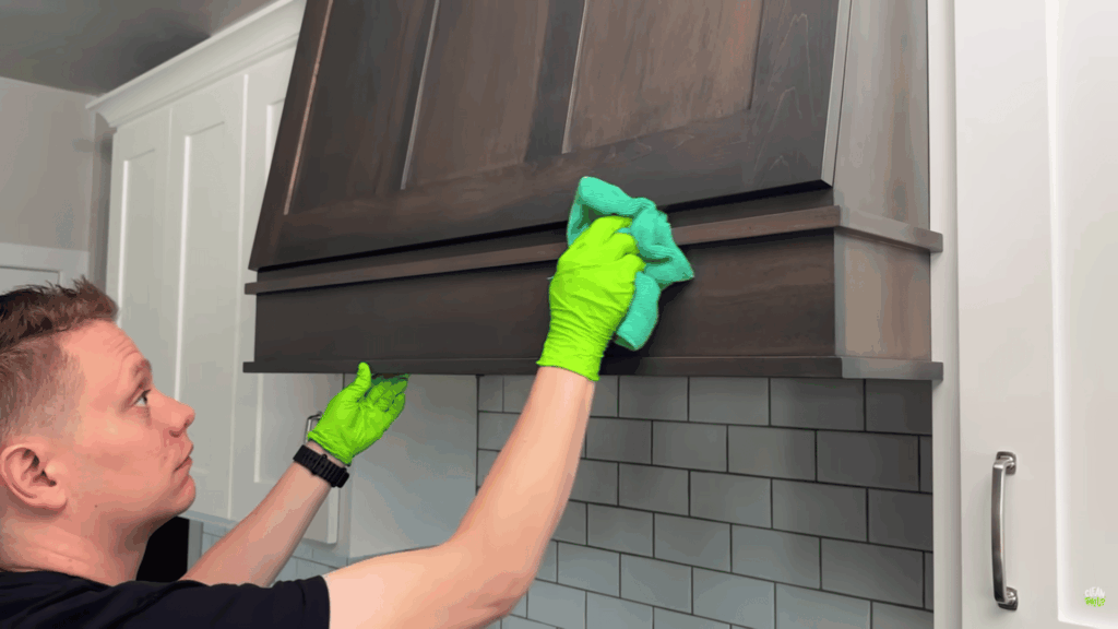 wiping wooden range hood with cloth to remove grease.