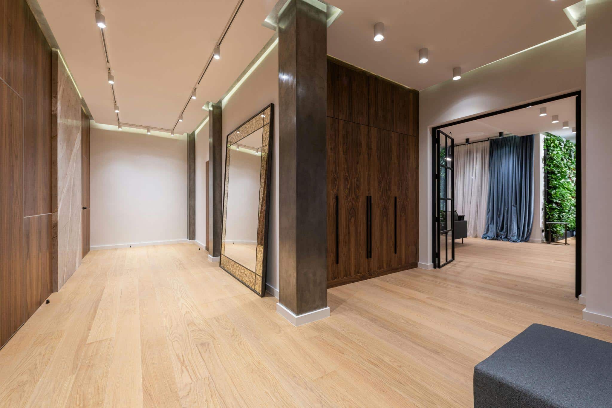 Apartment hallway with a mirror, wooden parquet, and walls.