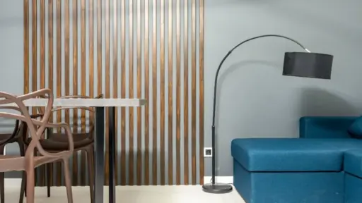 Modern living room with blue sofa, black floor lamp, and wooden slatted wall divider