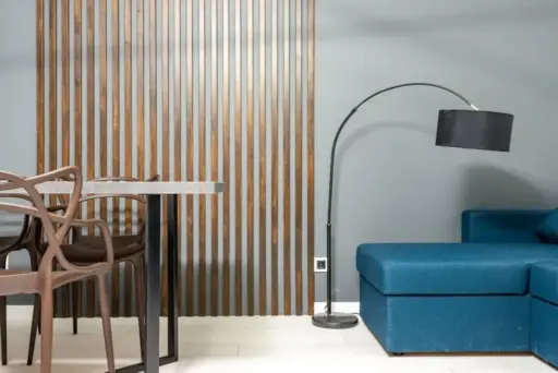 Modern living room with blue sofa, black floor lamp, and wooden slatted wall divider