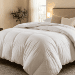 a neatly made bed covered with a thick fluffy white comforter in a warm and cozy bedroom with soft lighting