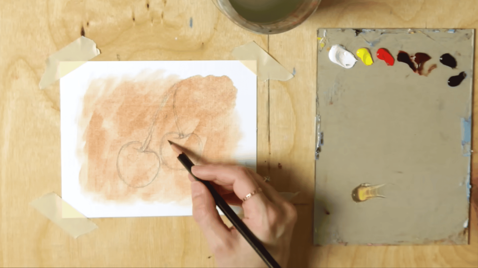 a pencil sketching basic cherry shapes onto a toned canvas surface as part of the oil painting for beginners process