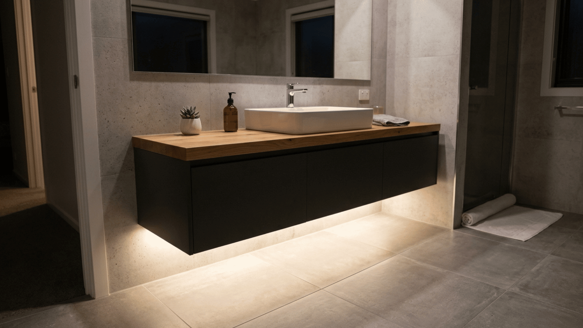 bathroom vanity with LED strip lighting underneath creating a soft floating glow.
