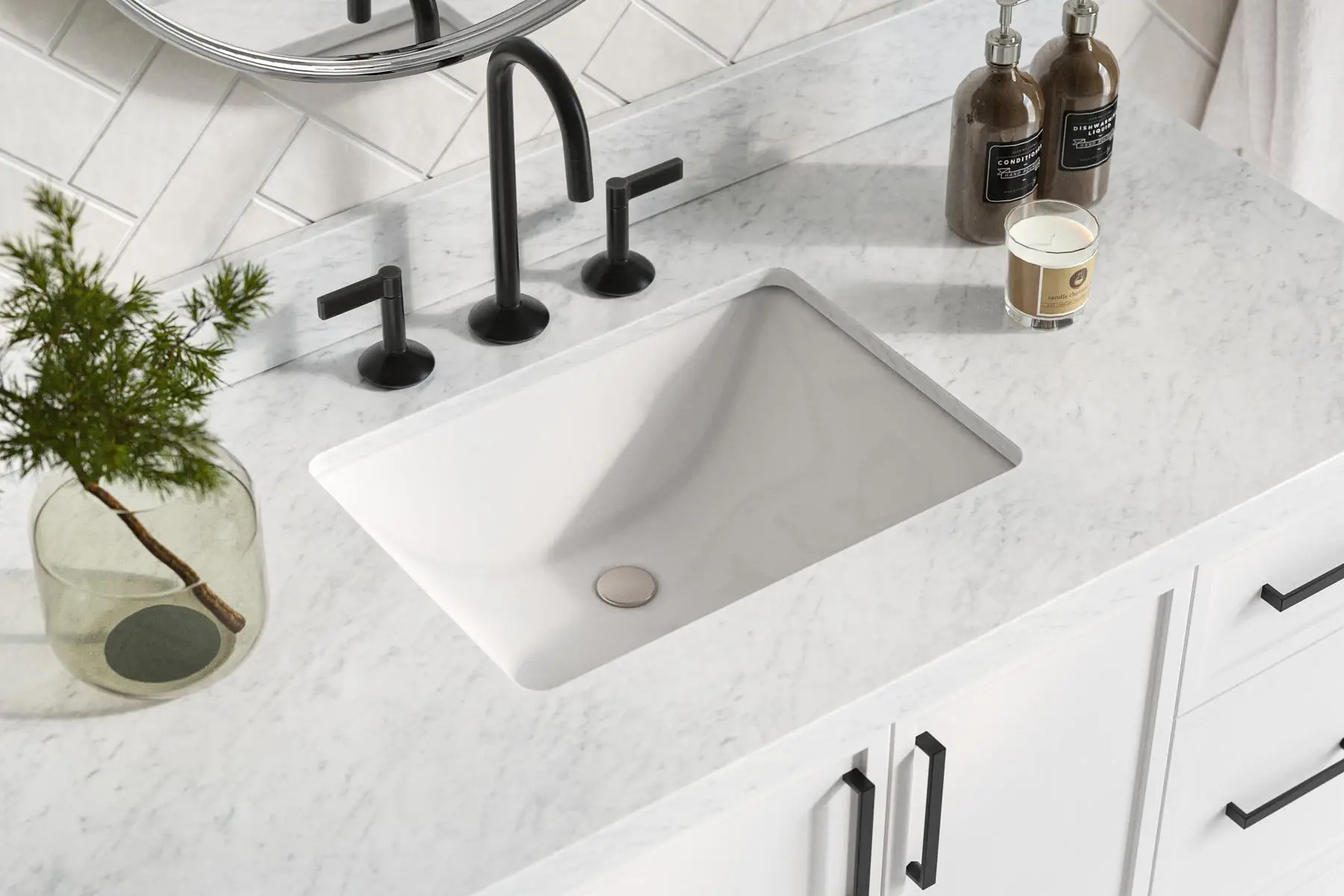 Marble bathroom countertop with black faucet, candle, and small plant in glass vase