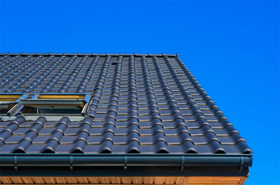Dark gray tiled roof with skylight under clear blue sky