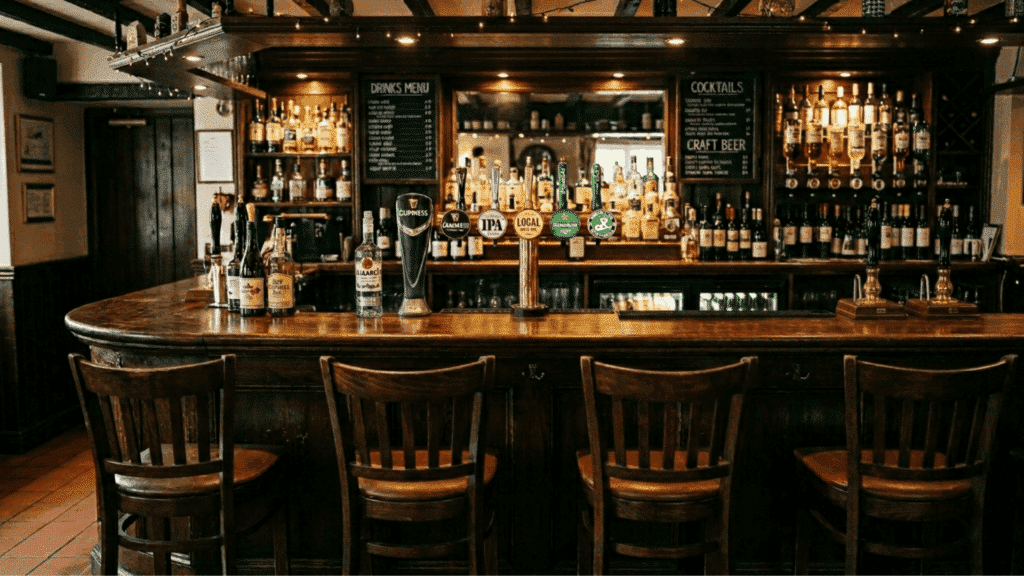 classic wooden bar with stools, liquor shelves, and warm lighting in a cozy pub setting.