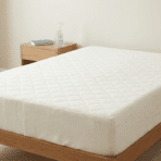 clean mattress placed on a wooden bed frame in a simple bedroom setting.