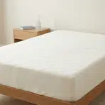 clean mattress placed on a wooden bed frame in a simple bedroom setting.