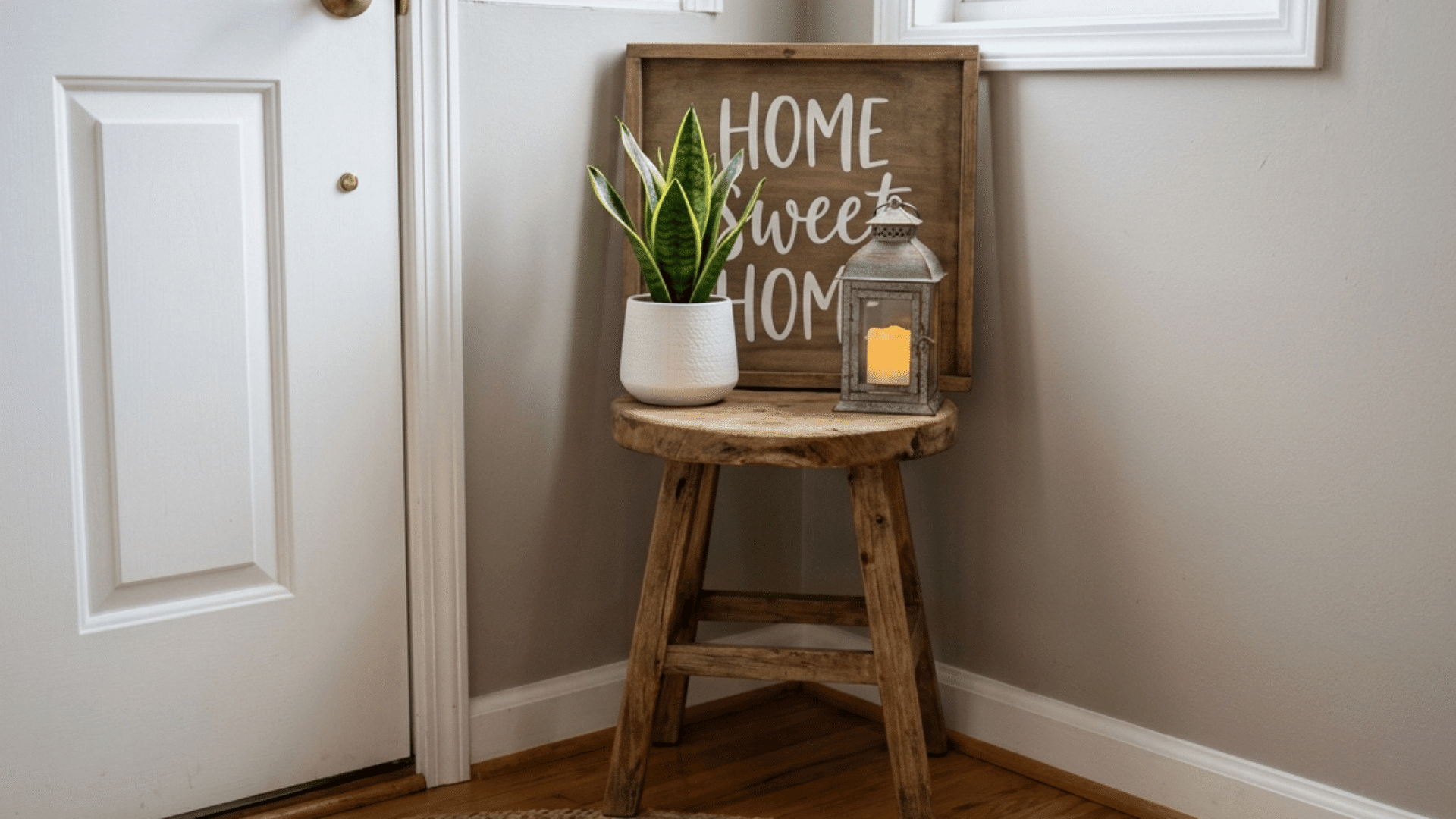 compact corner display with stool, plant, lantern, and home sign.