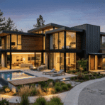 contemporary house exterior at night with glass walls and pool area.