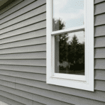 cost to install vinyl siding shown on a home exterior with gray panels white trim and two windows in natural light