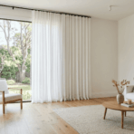curtains touch the floor in a modern living room with white linen floor length curtains and hardwood flooring