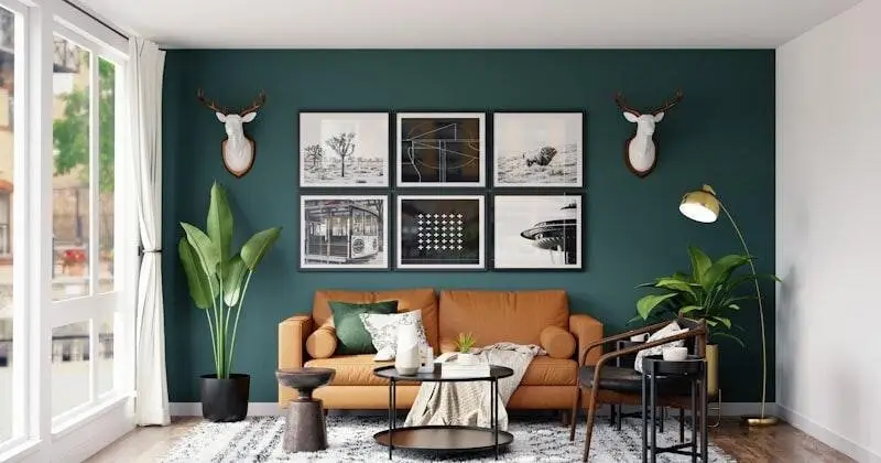 Warm living room with a tan sofa, green accent wall, and modern art above it