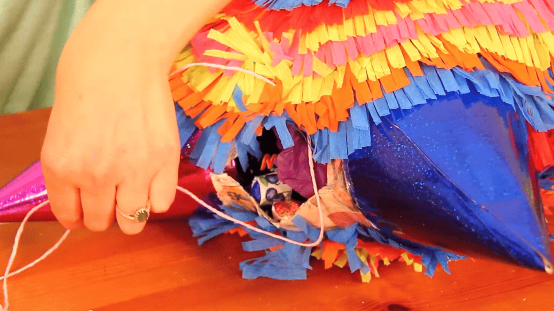 filling piñata with candy, sealing the hole with cardboard, and finishing with paper strips