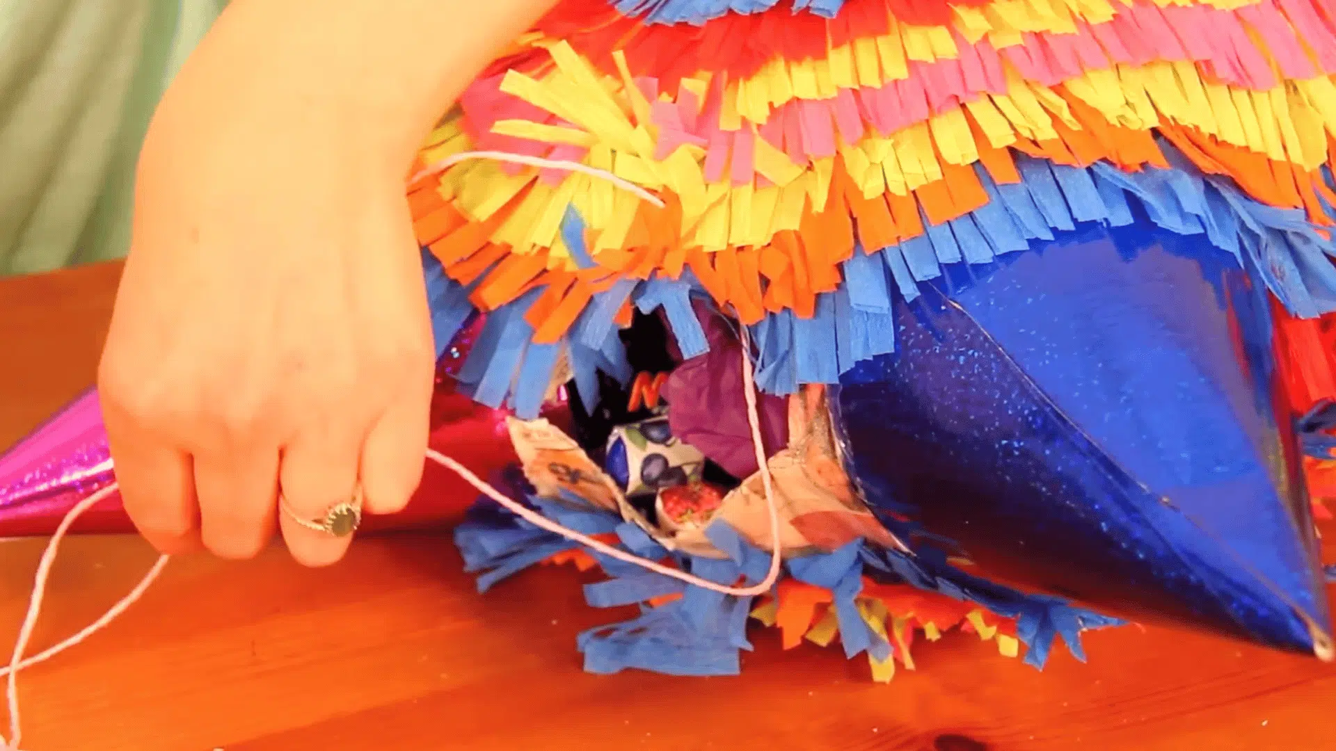 filling piñata with candy, sealing the hole with cardboard, and finishing with paper strips