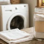 finished DIY reusable dryer sheets stored in a glass jar, ready for use with laundry for a fresh, clean scent.