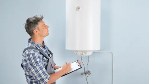 Maintenance worker inspecting a wall-mounted water heater with clipboard in hand