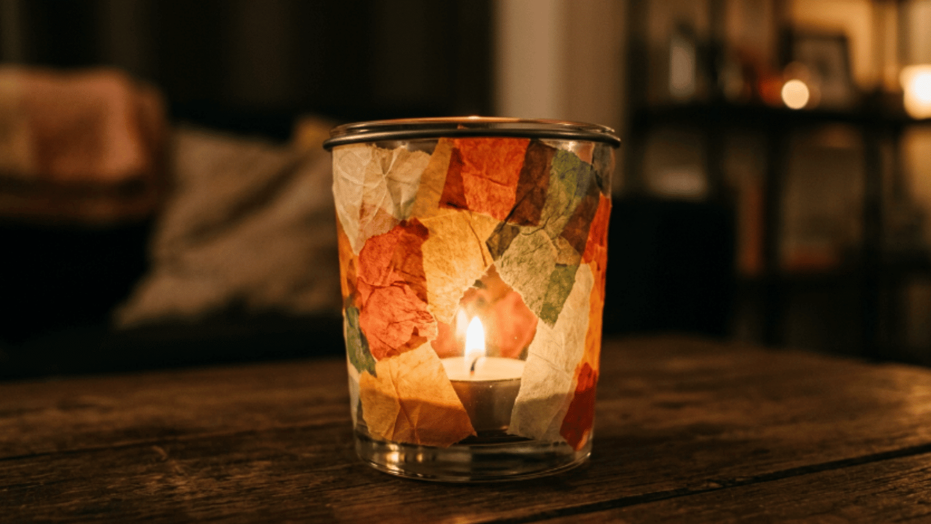 glass candle holder decorated with tissue paper glowing with candle light in cozy indoor setting