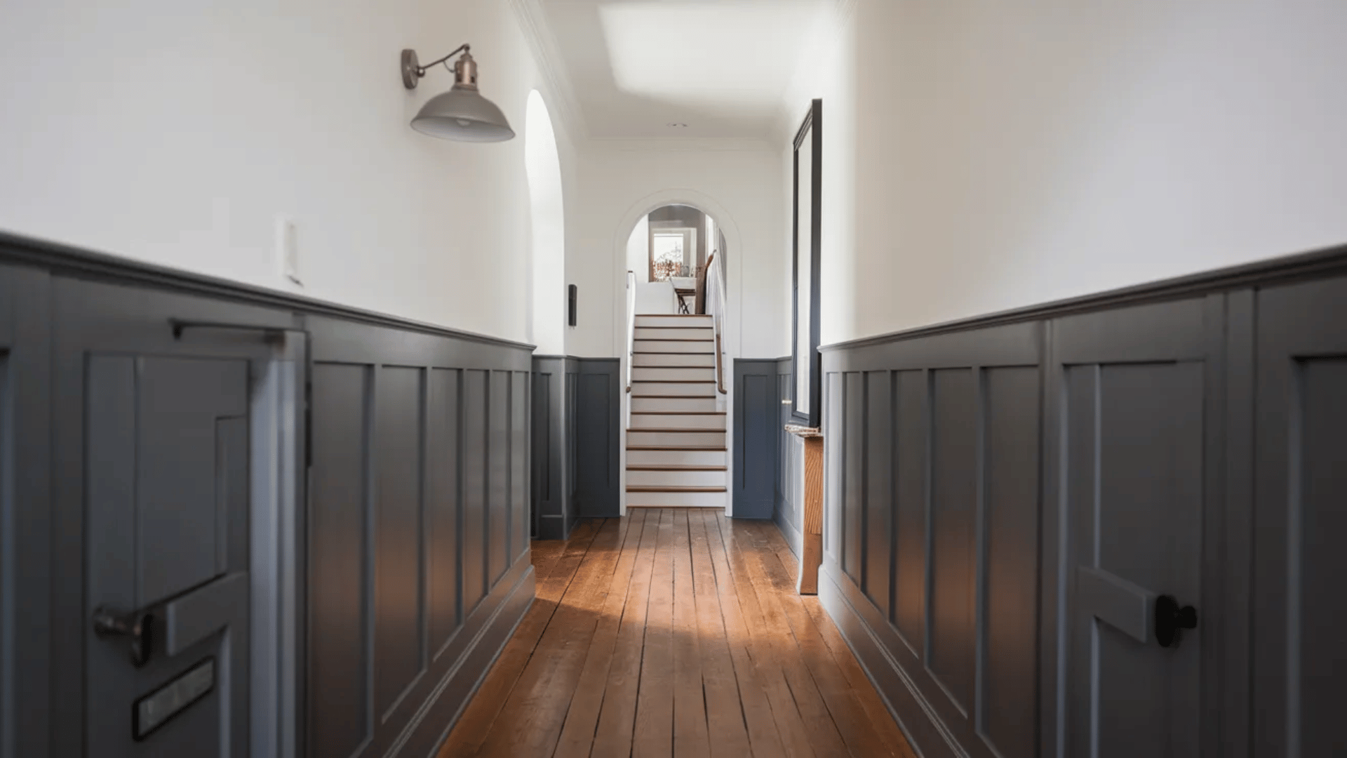 hallway with dark wainscoting, wood floor, and staircase leading up