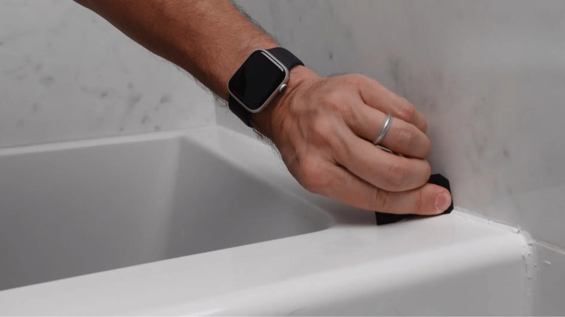hand smoothing fresh caulk bead along tub edge with tool for clean finish in bathroom (1)