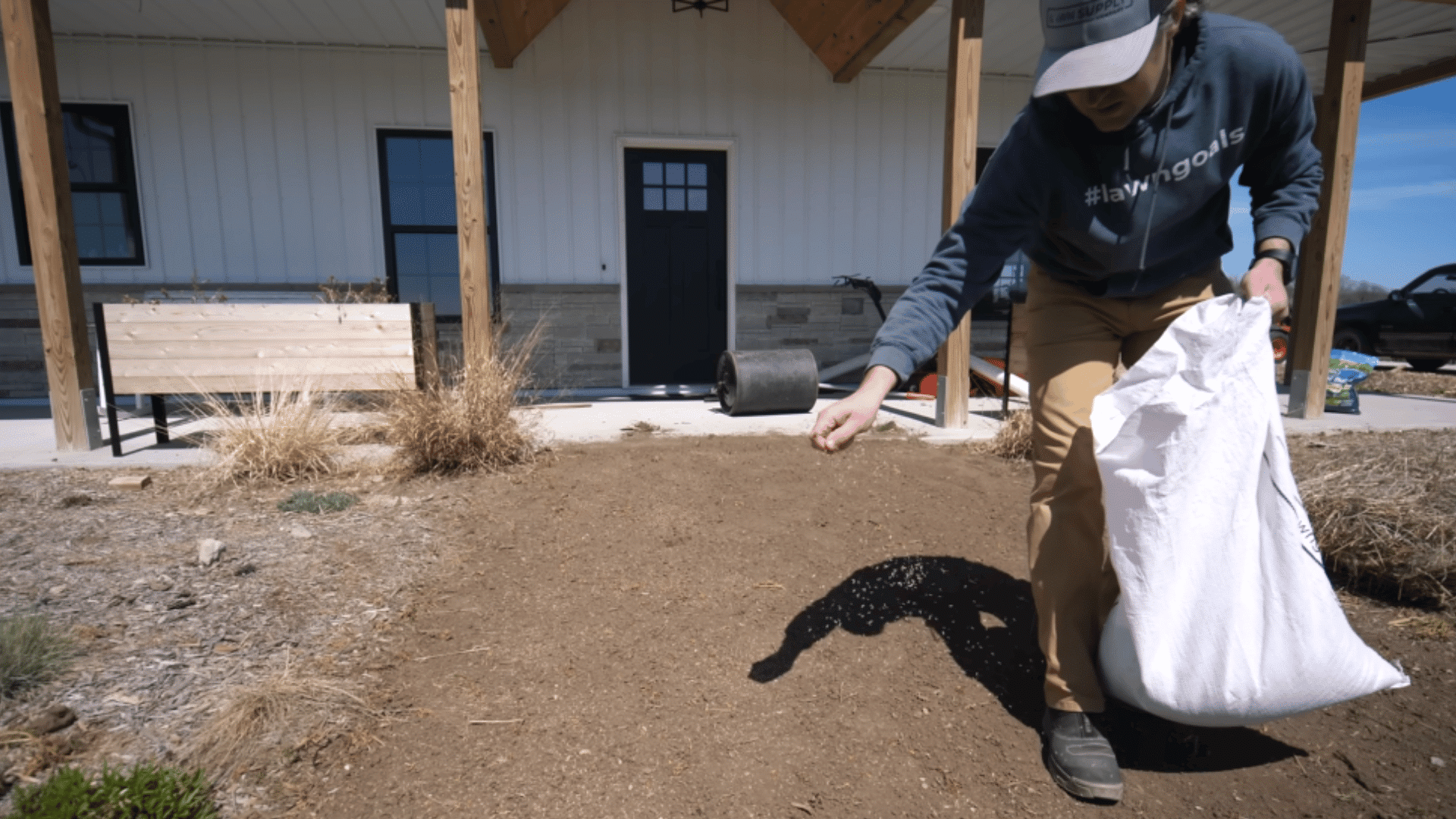 hand spreading grass seed evenly over prepared soil for balanced lawn growth