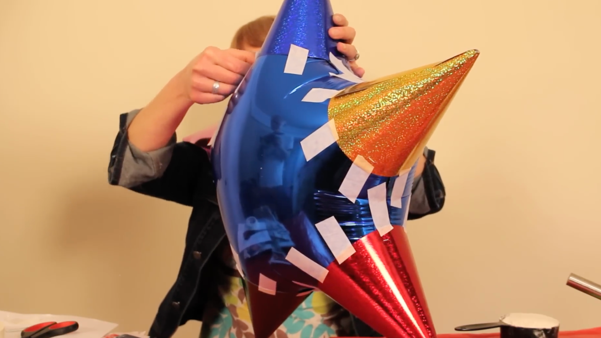 inflated balloon with party hats attached using tape to form a stable star shaped piñata base