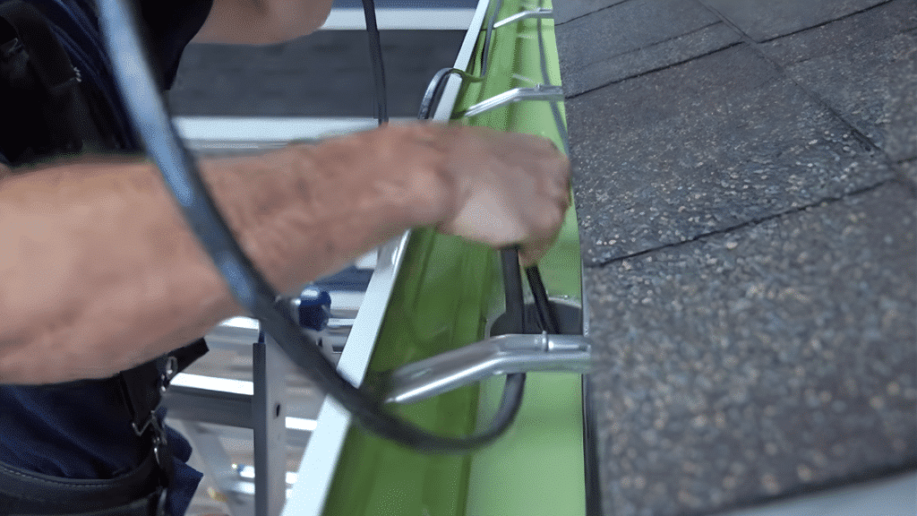 installing heat cable inside gutter with clips for secure placement.
