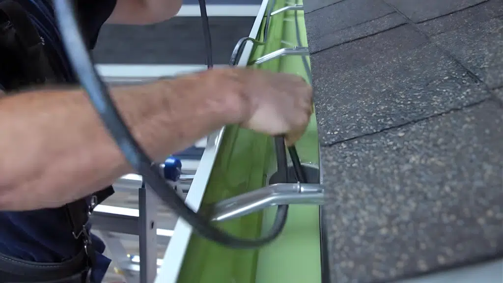 installing heat cable inside gutter with clips for secure placement.