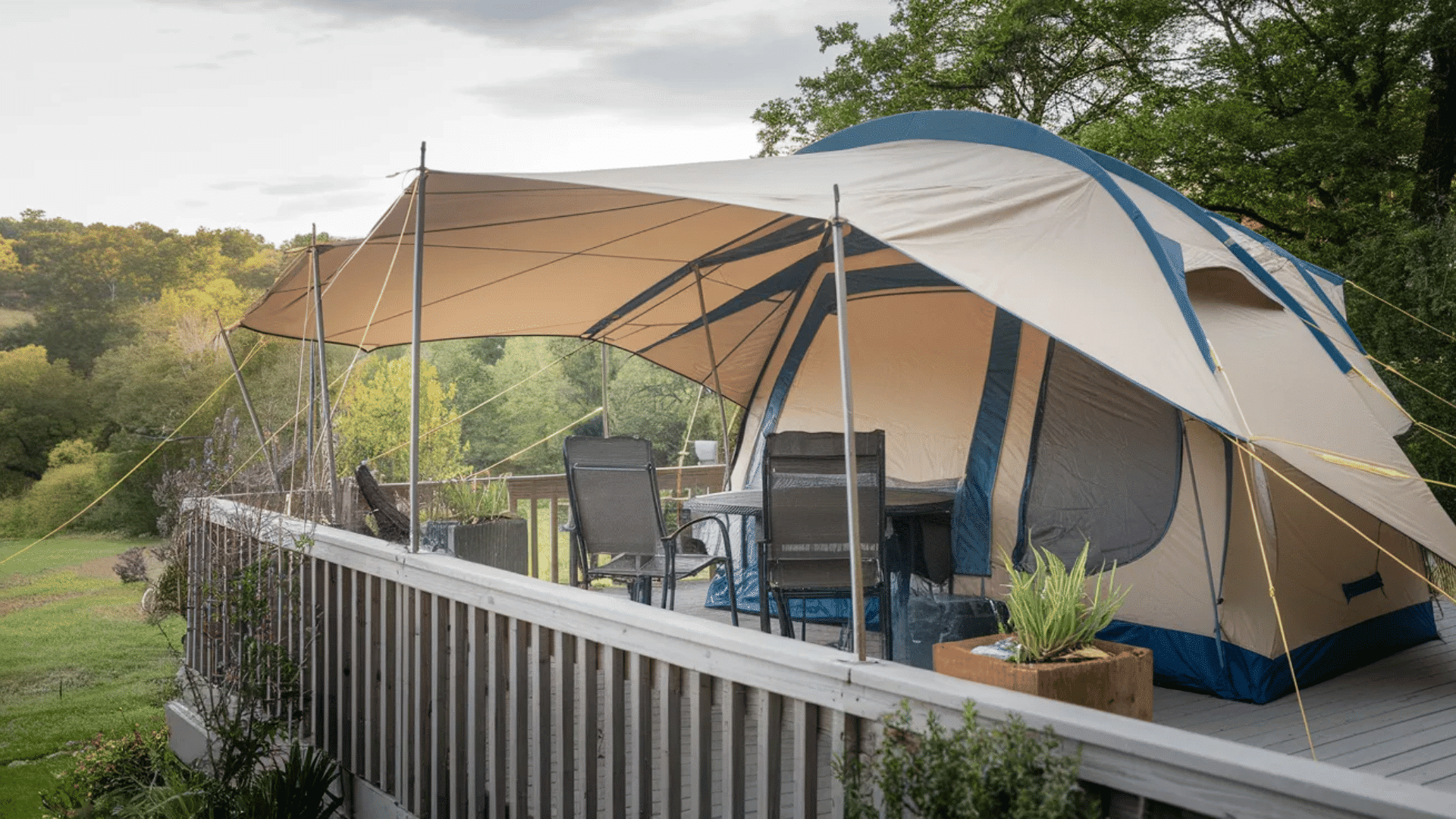 large camping tent with extended canopy set up on a wooden deck with outdoor chairs overlooking trees and a scenic hillside landscape