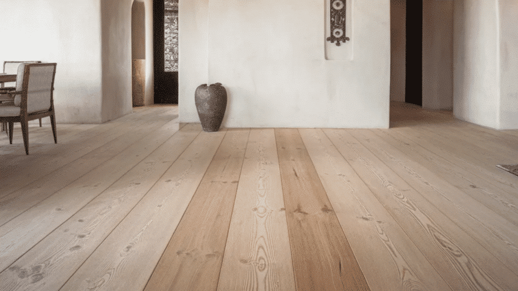 light wood plank flooring in stucco interior with arched doorways and exposed ceiling beams