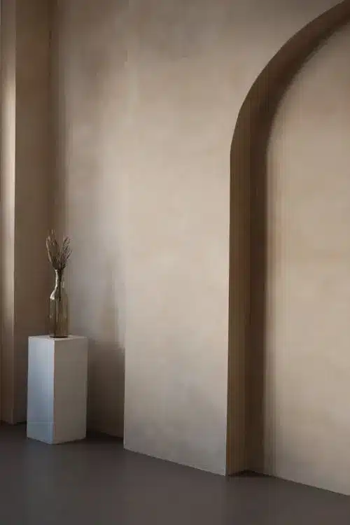 Elegant beige interior with tall vase on a white pedestal under soft light