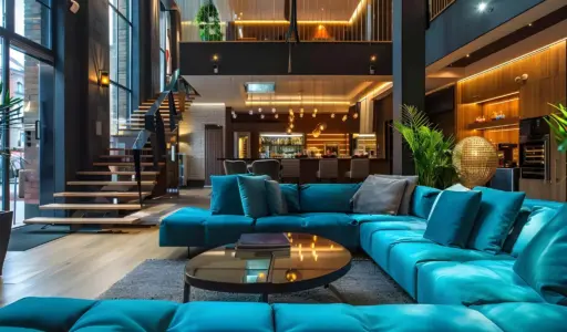 Luxurious open-plan living room with blue sectional sofa, glass coffee table, and modern staircase