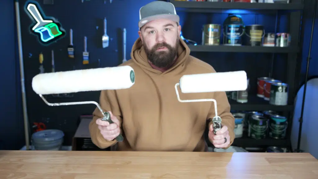 man holding two paint rollers in workshop with paint cans tools and shelves in background
