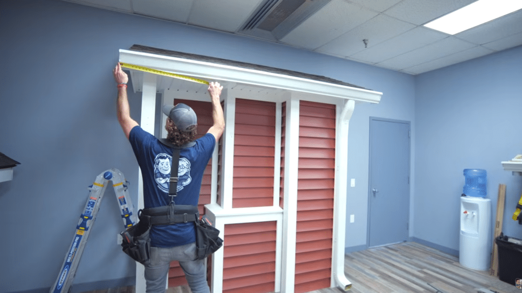 man measuring gutter length with tape before heat cable installation.
