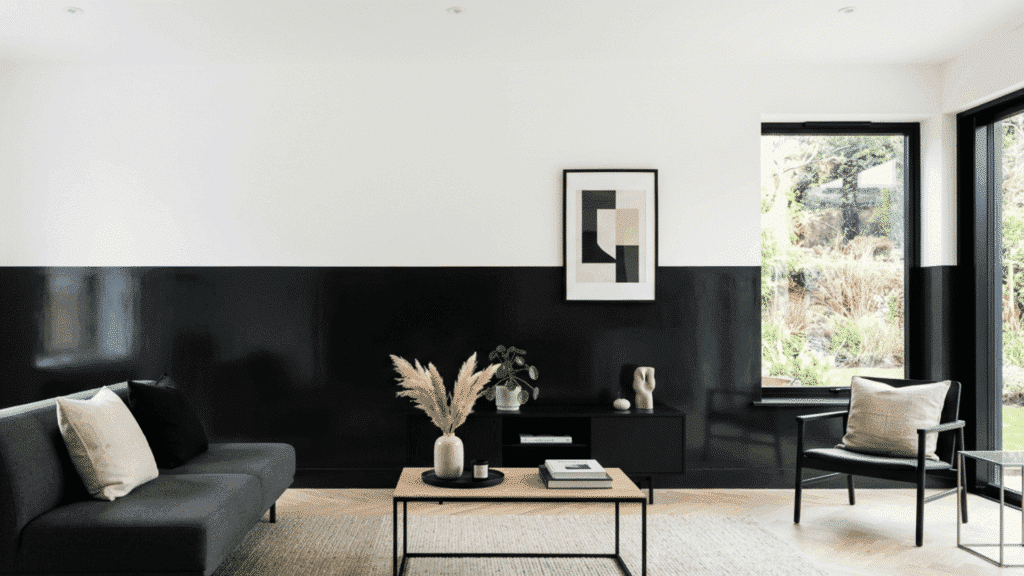 minimalist living room with black lower wall and bright white upper wall styled with simple furniture and minimal decor
