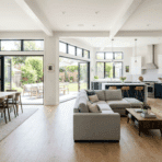 modern open-concept living room, dining area, and kitchen with large windows, natural light, and seamless indoor-outdoor connection