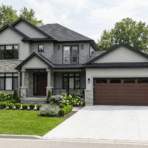 modern suburban house with attached garage, pitched roof and clean driveway with green lawn
