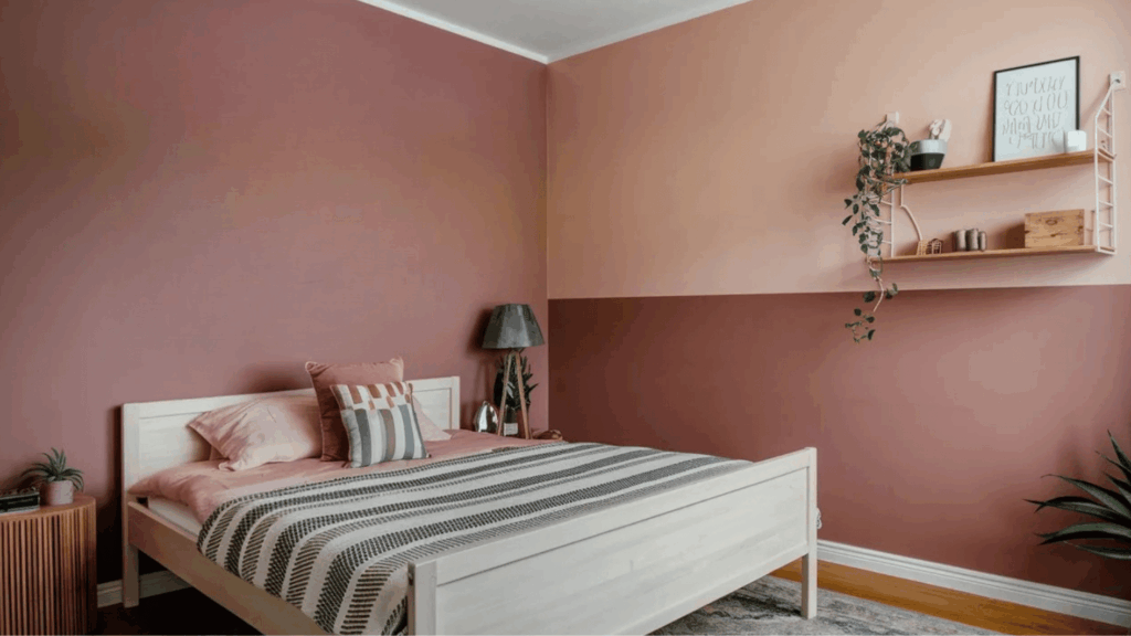 monochromatic pink bedroom with two-tone walls, wooden bed, decorative pillows, and wall art creating a warm, cohesive design