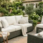 outdoor patio seating with clean beige cushions arranged on wicker furniture in a garden setting.