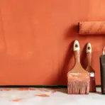 Painting roller and brushes on orange-painted surface indoors
