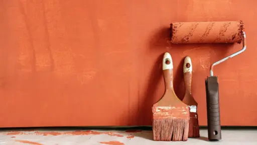 Painting roller and brushes on orange-painted surface indoors
