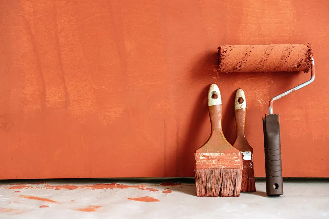 Painting roller and brushes on orange-painted surface indoors